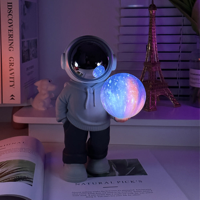 Holding the dreamy starry sky grey top + navy blue pants Creative Astronaut Bluetooth Speaker with 3D Starry Sky Lighting, Portable Wireless Moon Lamp Speaker – Perfect Gift for Space Enthusiasts
