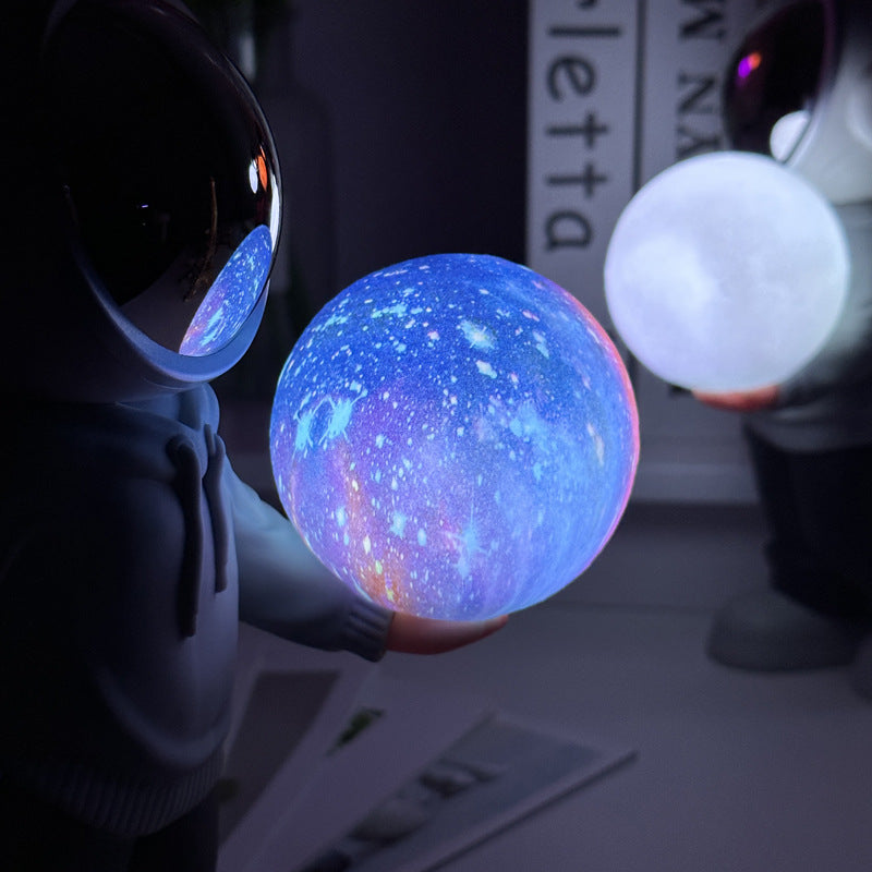 Holding the dreamy starry sky grey top + navy blue pants Creative Astronaut Bluetooth Speaker with 3D Starry Sky Lighting, Portable Wireless Moon Lamp Speaker – Perfect Gift for Space Enthusiasts